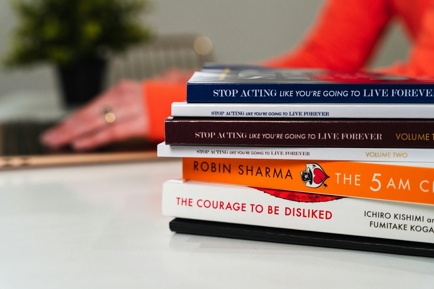 Stack of self-help books on a white table.